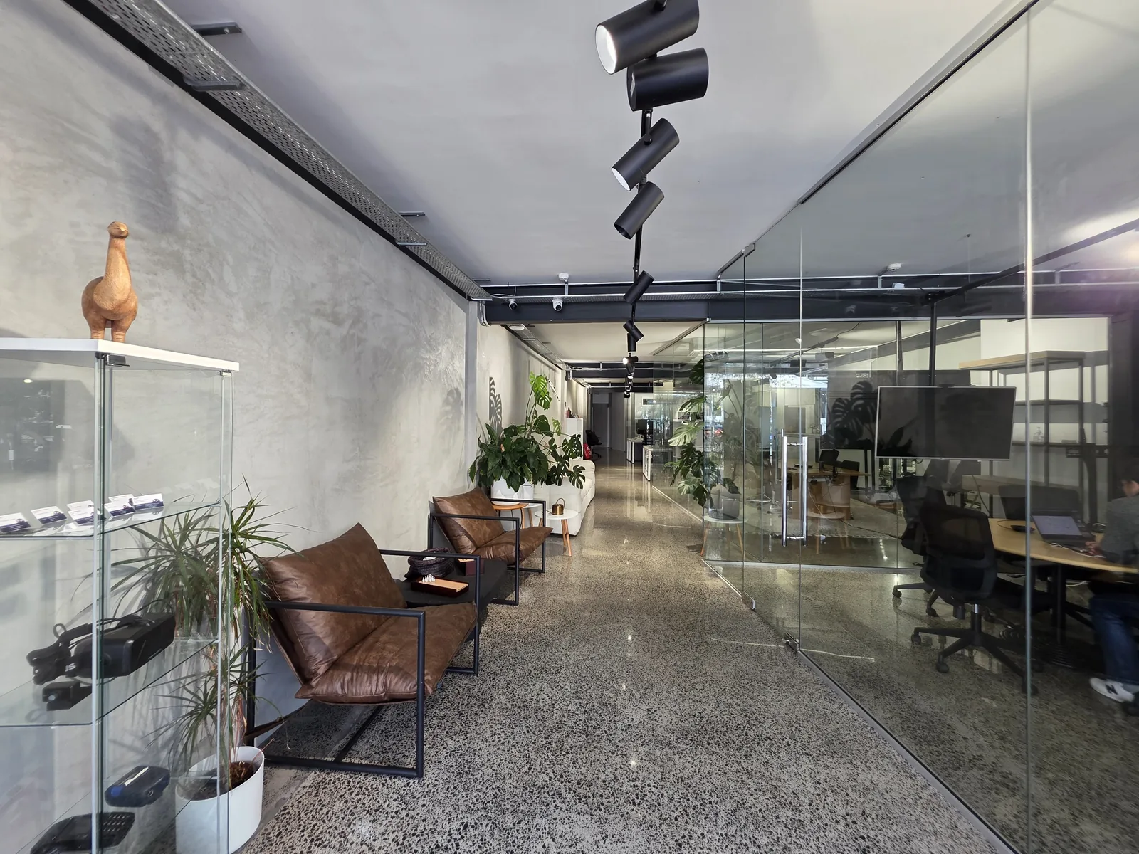The reception of the Applicable office in Auckland: leather chairs along a concrete wall and a glass-walled workspace