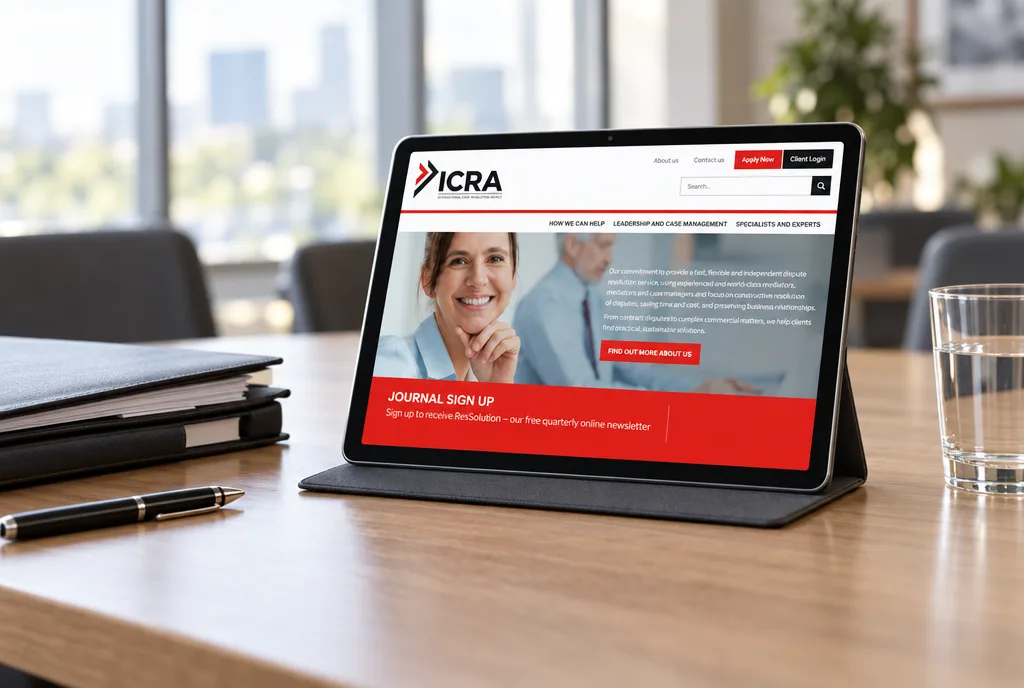 The ICRA website home page on a tablet propped on a meeting-room table beside case folders